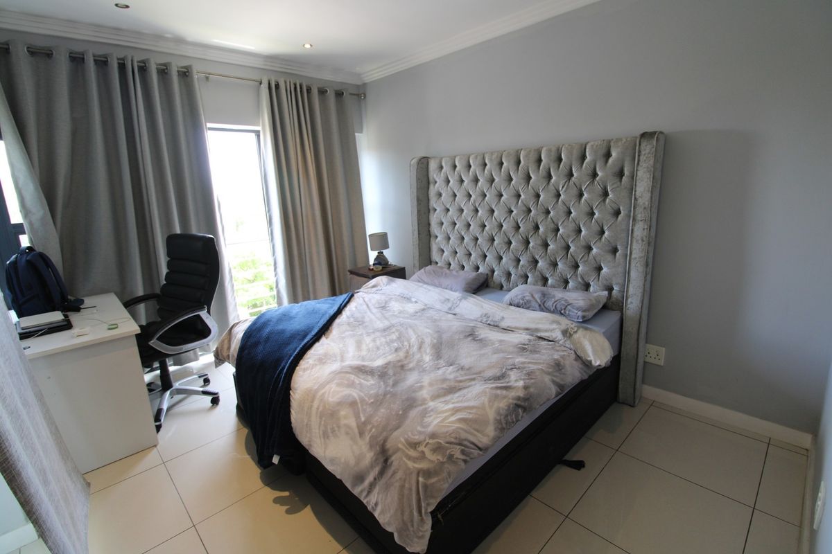 A well-lit bedroom featuring tiled flooring, recessed downlighting, and a sliding glass door providing access to an outdoor area.