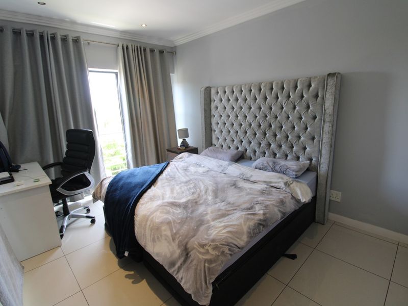 A well-lit bedroom featuring tiled flooring, recessed downlighting, and a sliding glass door providing access to an outdoor area.