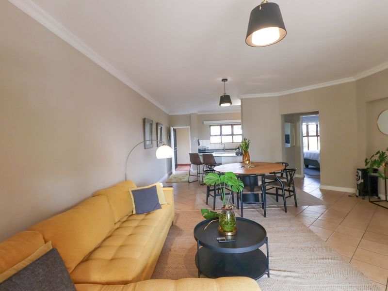 Spacious open-plan living and dining area featuring tiled flooring, neutral walls, and integrated kitchen space with modern pendant lighting.