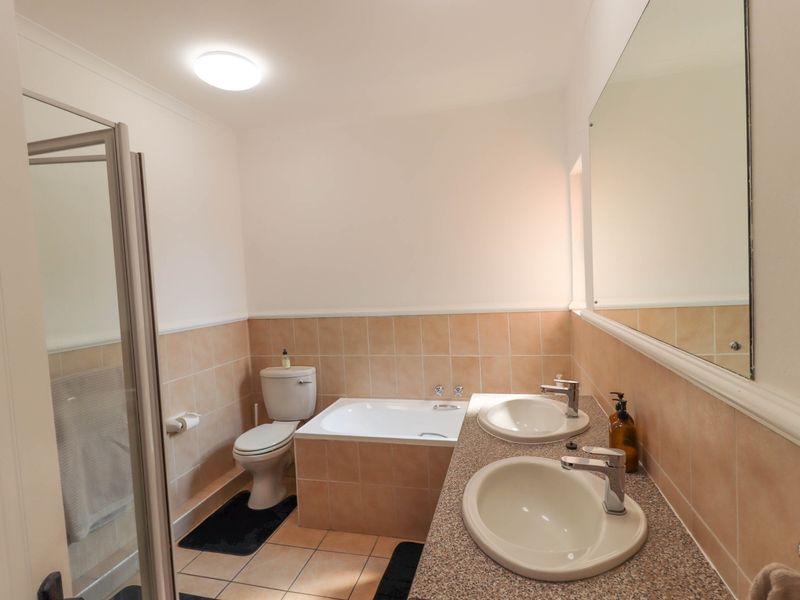 A functional bathroom featuring a dual vanity, built-in bathtub, and a separate shower enclosure with neutral wall and floor tiling.