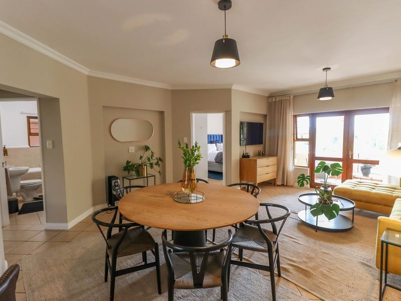 An open-plan living and dining area featuring tiled floors, coved ceilings, pendant lighting, and sliding glass doors leading to an outdoor space.