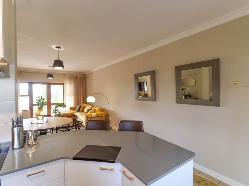 An open-plan living and kitchen area featuring a modern kitchen island with stone countertops, built-in hob, and seamless flow to the living space.