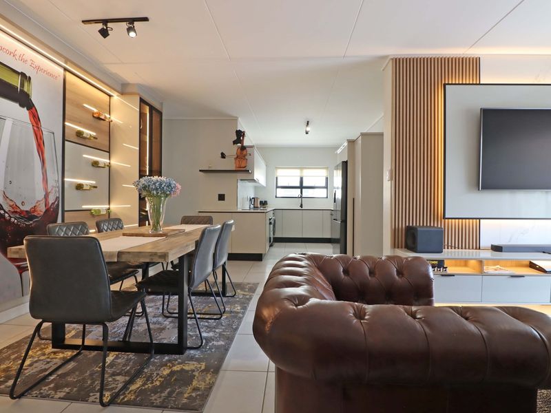 Modern open-plan living and dining area featuring a stylish slatted timber wall, built-in wine display, and a sleek, well-appointed kitchen.