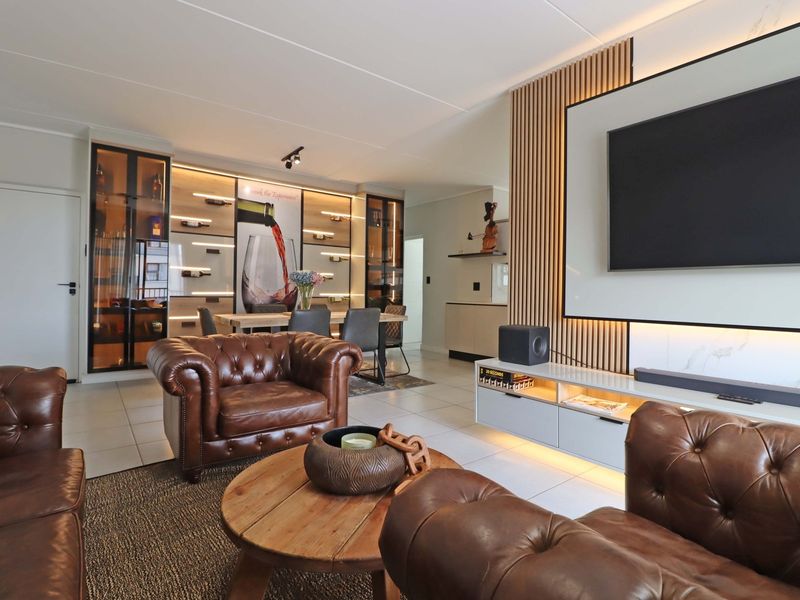 Modern open-plan living and dining area featuring a sophisticated slatted timber feature wall, integrated wine display cabinetry, and high-quality tiled flooring.