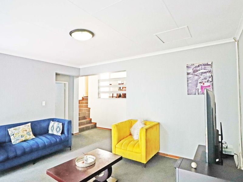 A living room area featuring carpeted flooring, a staircase leading to another level, and neutral wall finishes.
