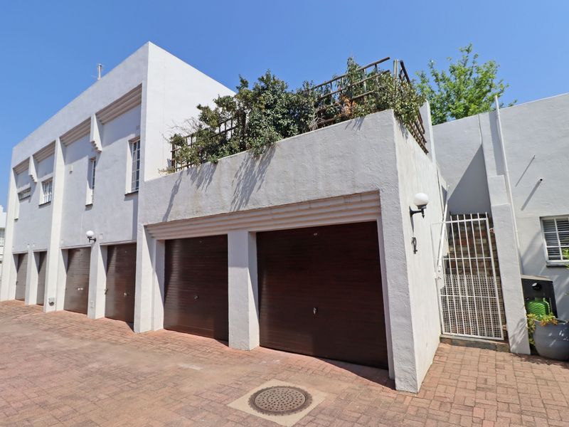 Exterior view of a residential apartment complex featuring double garage doors, paved driveway access, and an elevated terrace area.