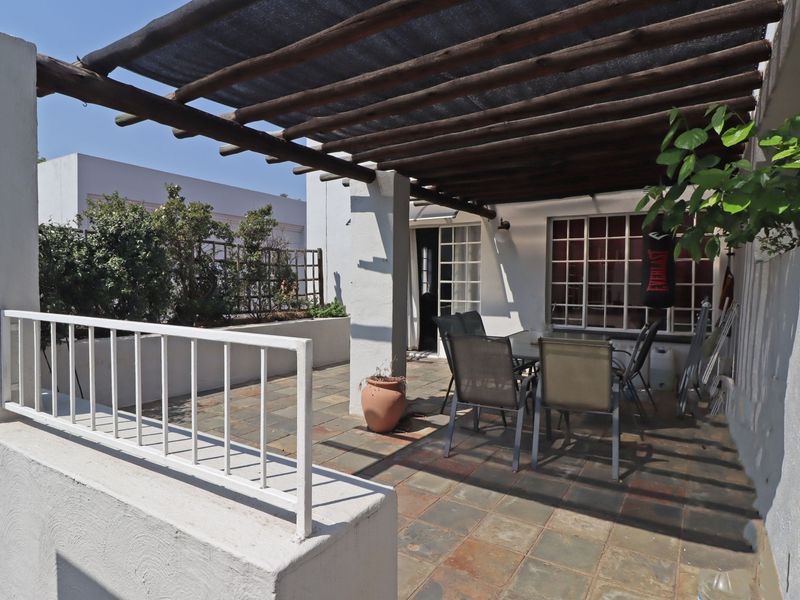 Covered outdoor patio featuring a timber pergola, slate tile flooring, and a metal balustrade, providing a functional space for outdoor living.