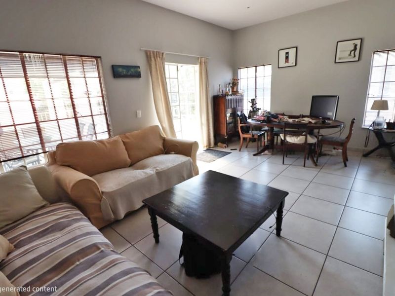 Open-plan living and dining area featuring neutral tiled flooring, large windows with venetian blinds, and access to the exterior via french doors.