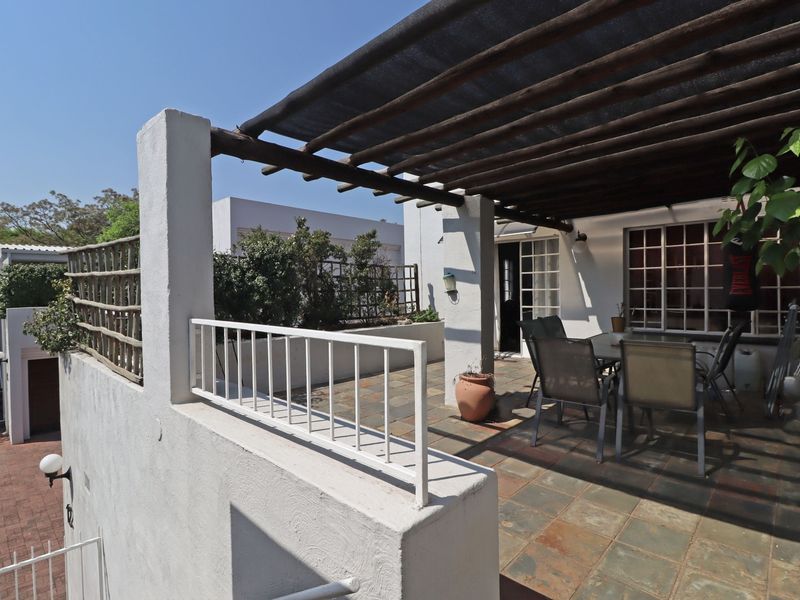 Spacious outdoor patio featuring a timber pergola with shade cloth, slate tile flooring, and a built-in masonry planter box.