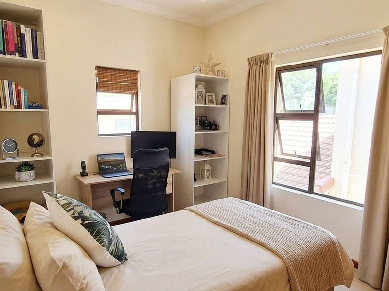 A well-maintained bedroom featuring built-in shelving, neutral wall finishes, and large windows that provide natural light.
