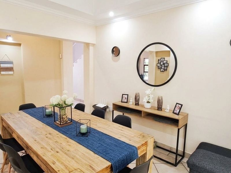 An open-plan dining area featuring tiled flooring, cove ceiling details, and a seamless transition into the adjacent kitchen space.