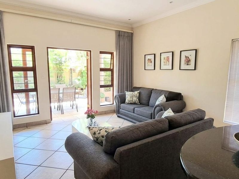 An open-plan living area featuring tiled floors, neutral walls, and a sliding glass door providing direct access to the outdoor patio space.