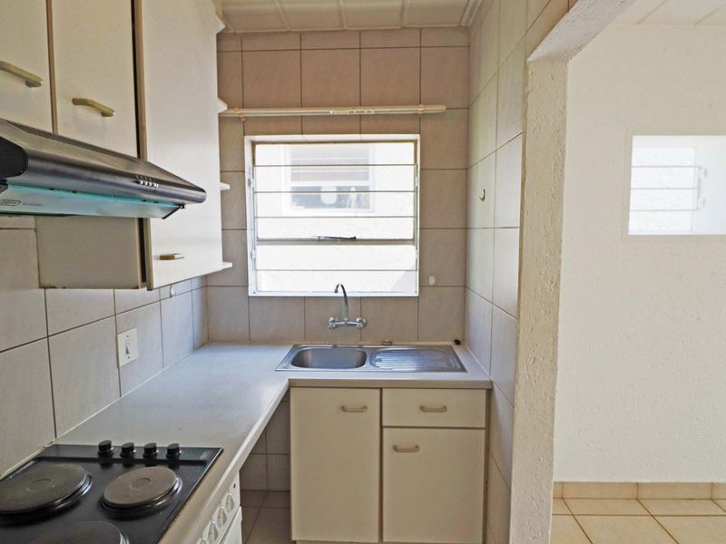 Compact kitchen featuring built-in cabinetry, a stainless steel sink, and an electric hob with an extractor fan.