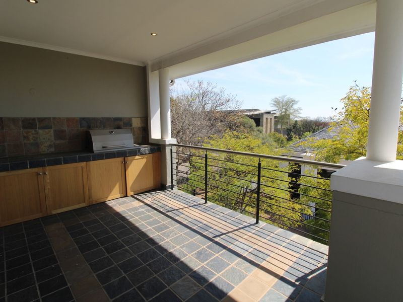 Covered balcony featuring a built-in braai, tiled flooring, and metal railings, offering an outdoor entertainment space with pleasant views.