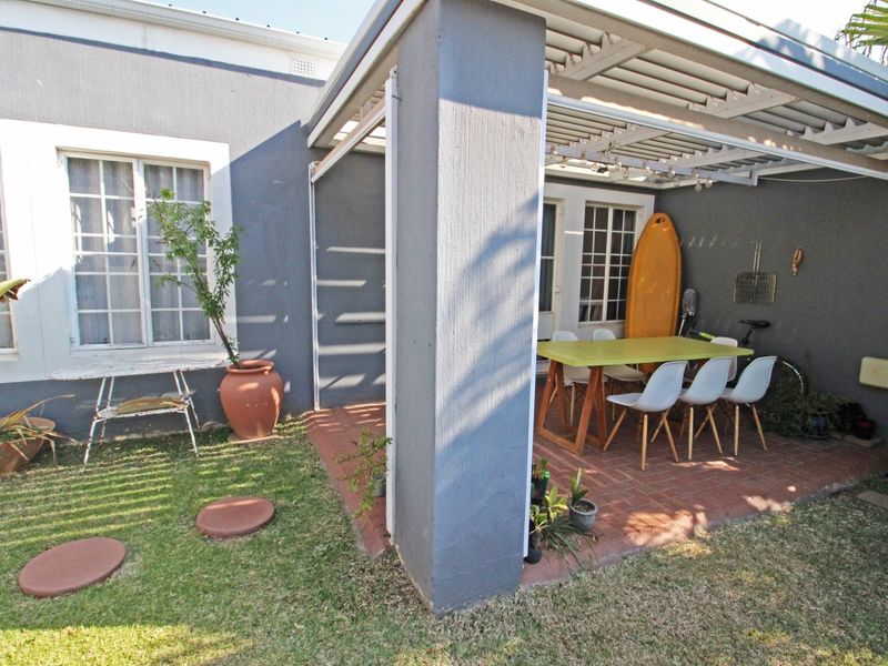 A covered patio area featuring brick paving and a pergola structure, providing a functional outdoor space for relaxation and dining.