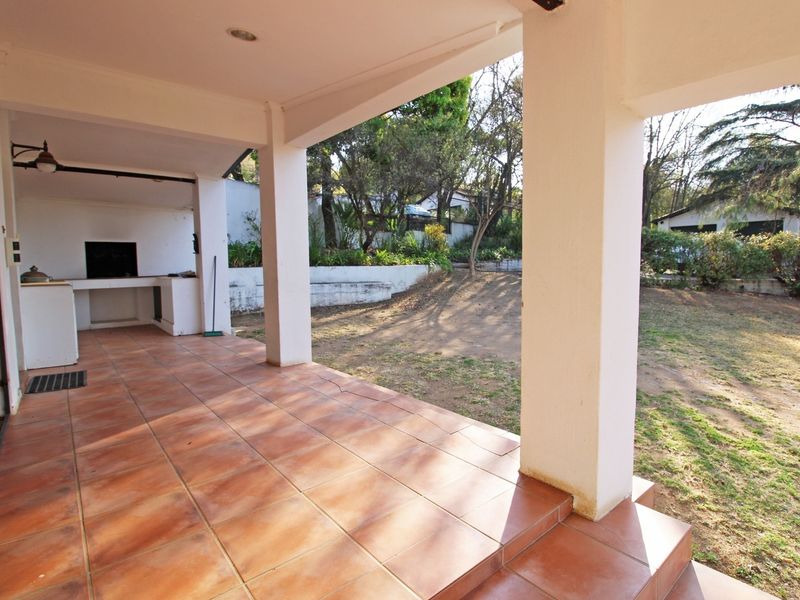 Covered patio area featuring a built-in braai, tiled flooring, and direct access to the rear garden space.