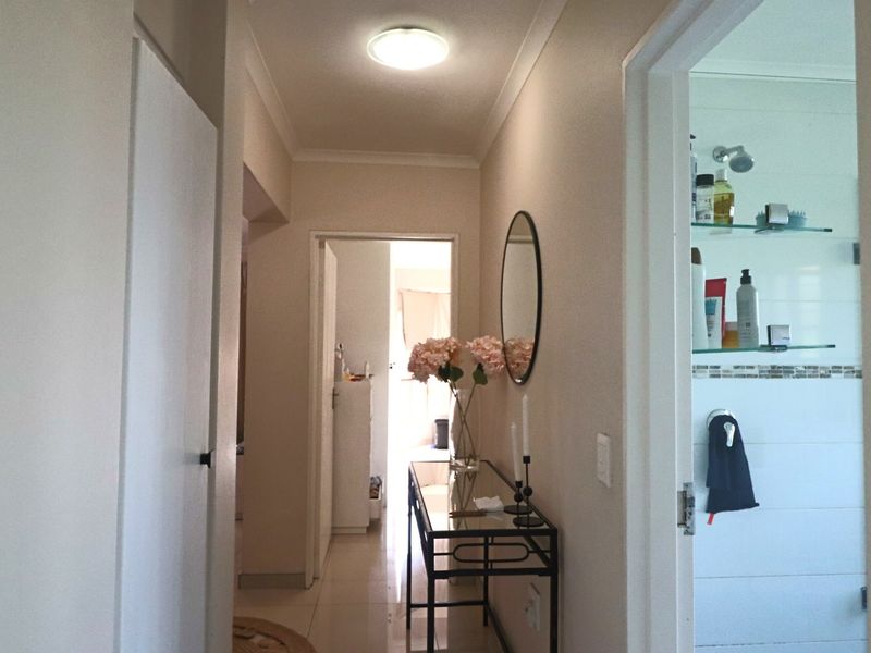 A functional hallway connecting interior spaces, featuring tiled flooring, neutral wall finishes, and access to an adjacent bathroom.