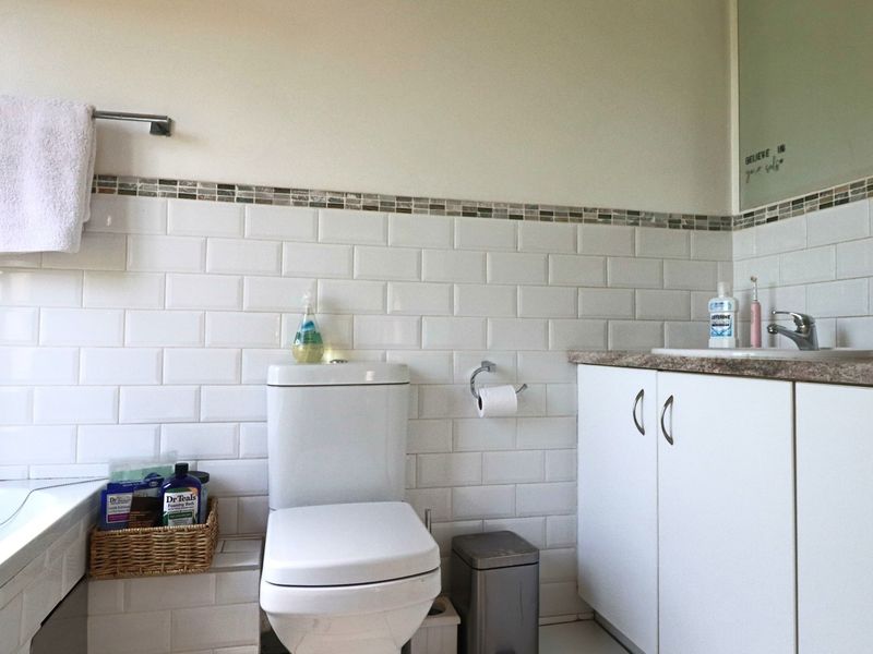 A clean bathroom featuring white subway wall tiles, a vanity cabinet with a laminate countertop, and a built-in bathtub.