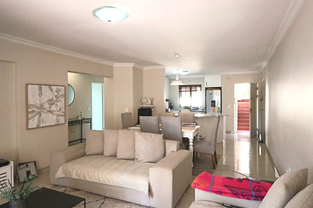 Open plan living and dining area featuring tiled flooring, neutral walls, and a functional kitchen layout with an island.