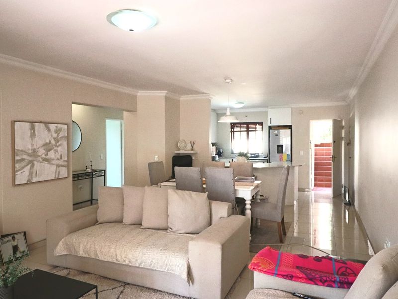Open plan living and dining area featuring tiled flooring, neutral walls, and a functional kitchen layout with an island.