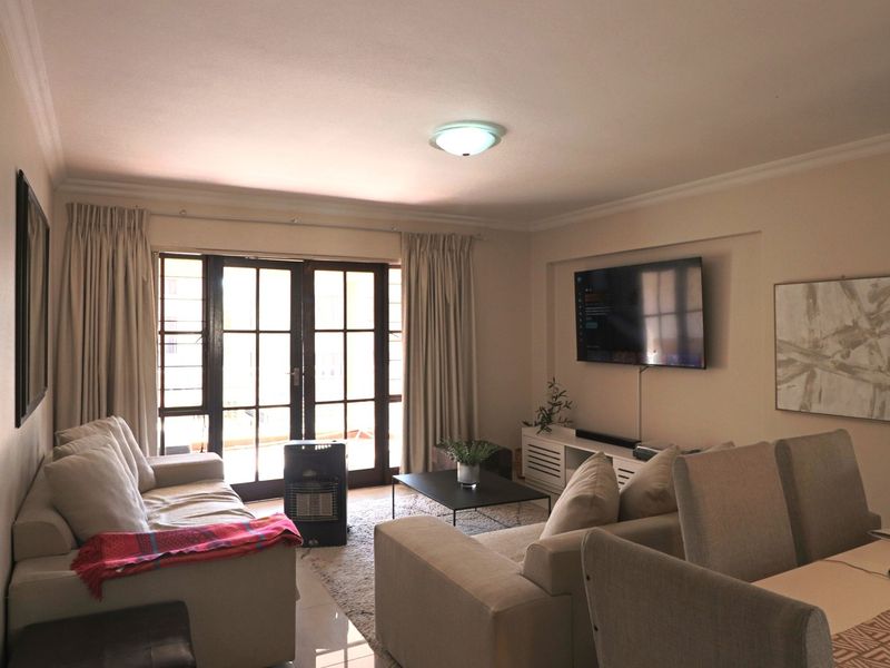 Open plan living and dining area featuring tiled floors, coving, and large french doors providing access to the outdoor space.