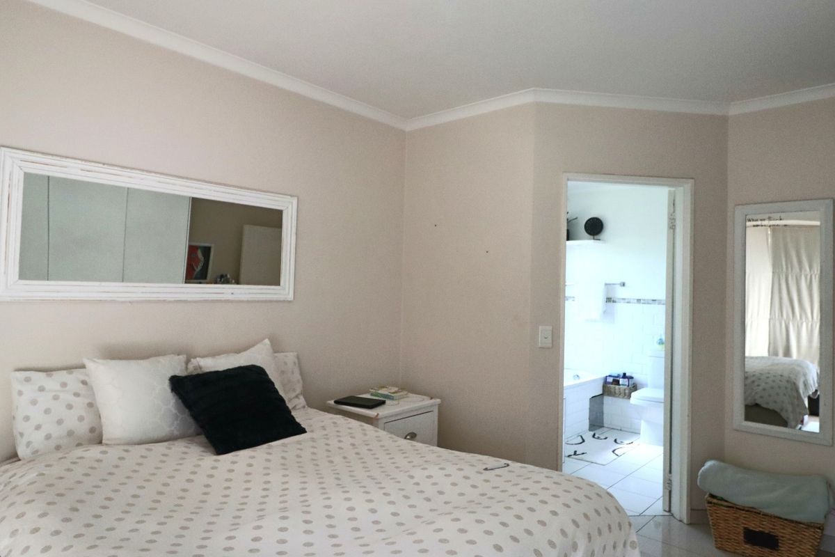 A bedroom featuring neutral wall tones and tiled flooring, with direct access to an adjoining bathroom.