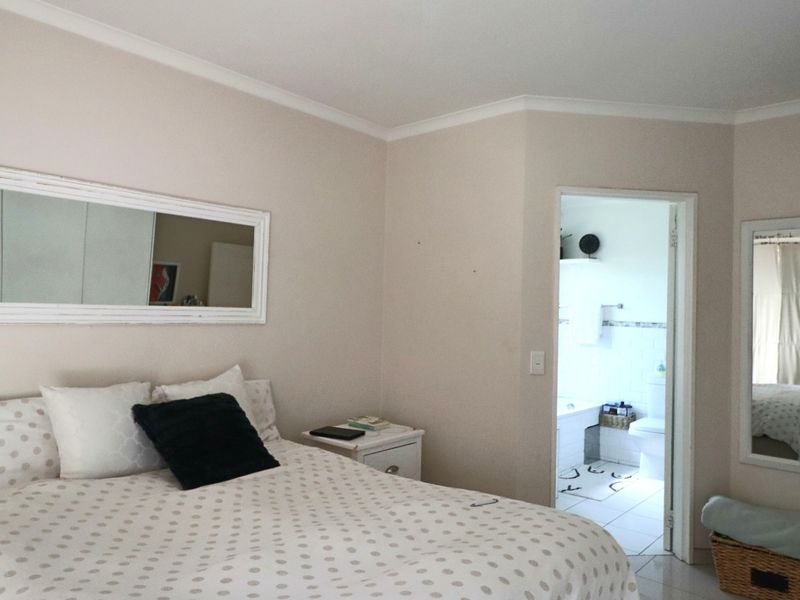 A bedroom featuring neutral wall tones and tiled flooring, with direct access to an adjoining bathroom.