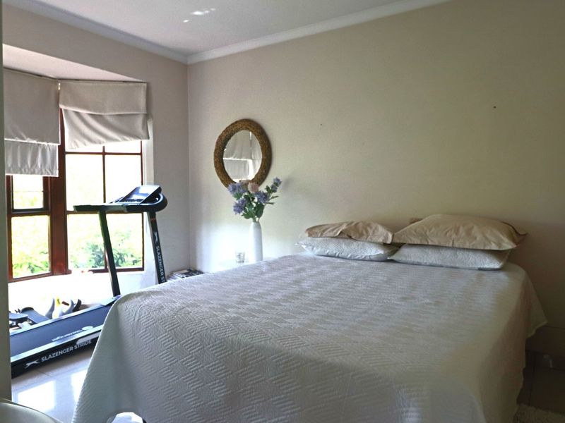 A bedroom featuring a bay window with natural light, tiled flooring, and neutral wall finishes.
