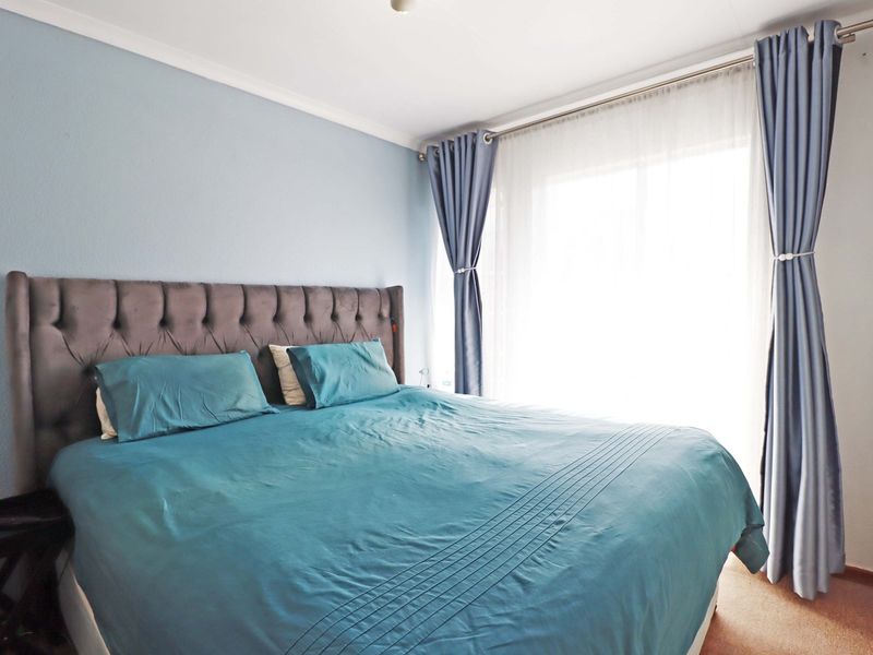 A well-lit bedroom featuring neutral wall finishes and a sliding door providing access to the exterior.
