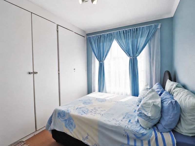 A functional bedroom featuring built-in cupboards, carpeted flooring, and coving, offering a comfortable and practical living space.