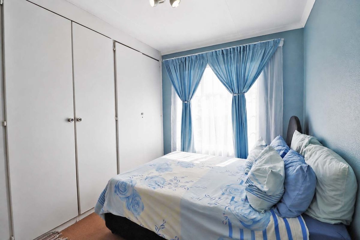 A functional bedroom featuring built-in cupboards, carpeted flooring, and coving, offering a comfortable and practical living space.