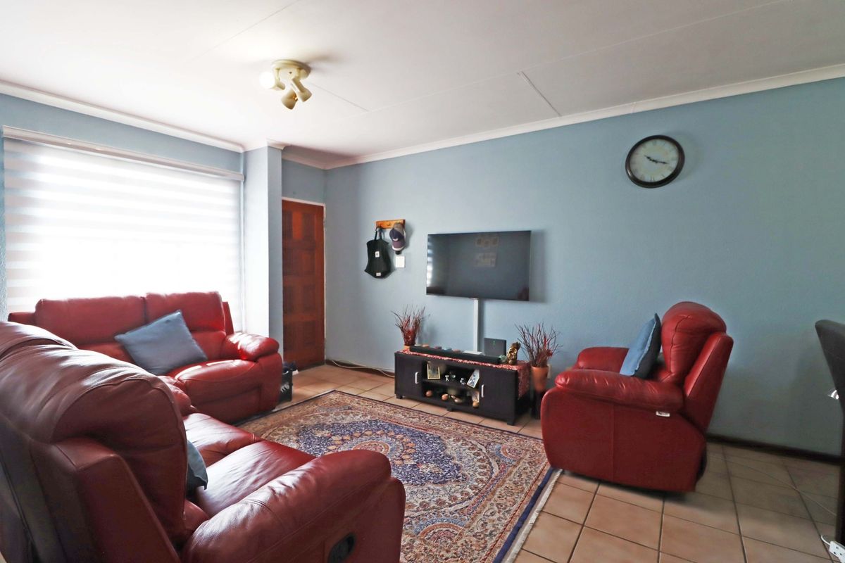 A living room featuring tiled flooring, neutral wall paint, and a window with fitted blinds, providing a functional and comfortable living space.