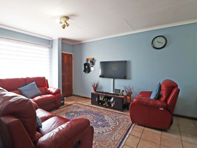 A living room featuring tiled flooring, neutral wall paint, and a window with fitted blinds, providing a functional and comfortable living space.