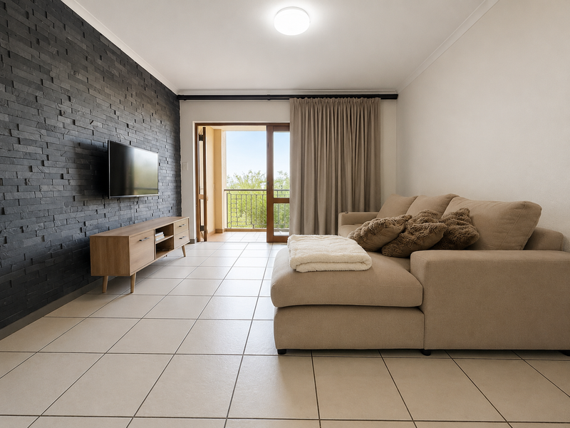 A bright living room featuring a modern dark stone feature wall, neutral tiled flooring, and direct access to a private balcony through sliding glass doors.