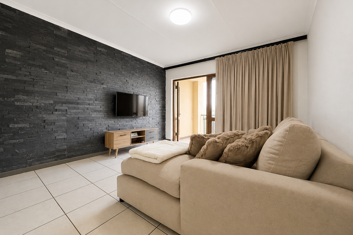 A well-maintained living room featuring a striking dark stacked stone feature wall, neutral tiled flooring, and direct access to an outdoor balcony.