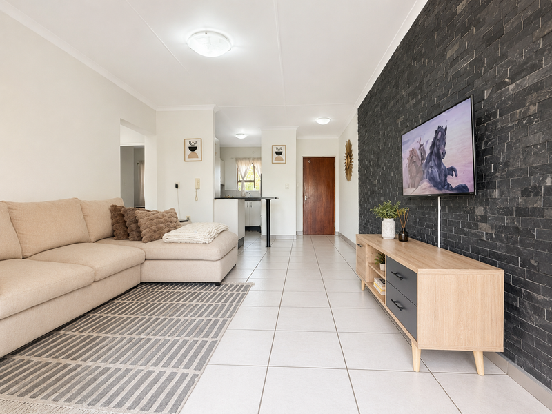 Open-plan living area featuring a striking dark stone feature wall, neutral ceramic floor tiles, and recessed lighting, creating a modern and cohesive living space.