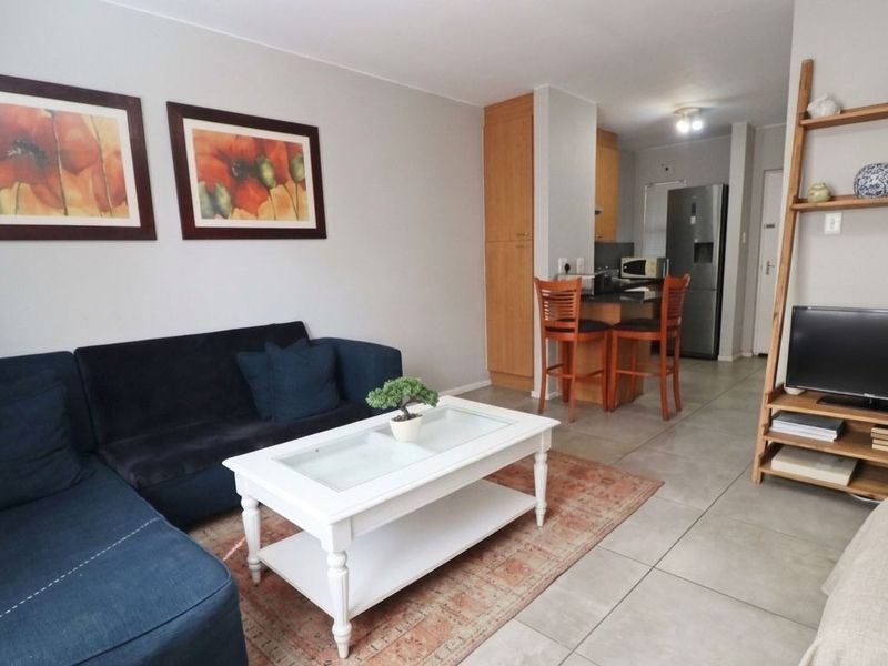 Open-plan living area featuring tiled flooring and a functional kitchen with a breakfast counter, creating a cohesive and practical living space.