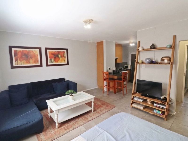 Open-plan living area featuring tiled flooring and a functional kitchen with built-in cabinetry and a breakfast counter.