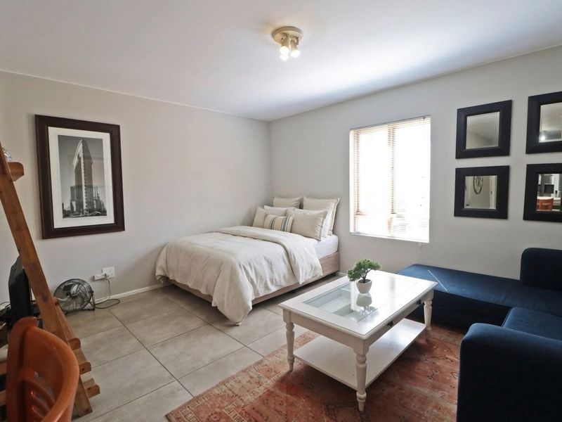 A well-maintained bedroom featuring neutral wall tones, tiled flooring, and natural light provided by a window with venetian blinds.