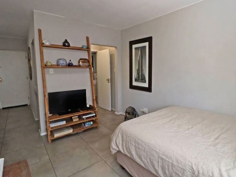 A bedroom featuring neutral wall tones and tiled flooring, providing a functional and well-maintained living space.