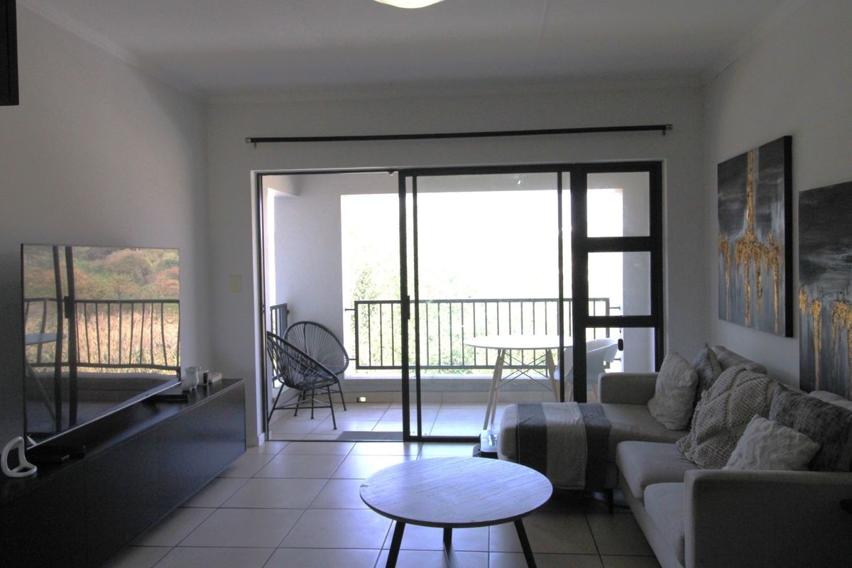 A living room featuring tiled flooring and a large sliding glass door that provides direct access to an outdoor balcony area.