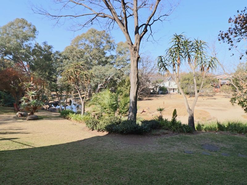 A well-maintained garden area featuring mature trees, landscaped lawn, and natural rockery elements, providing a peaceful outdoor setting.
