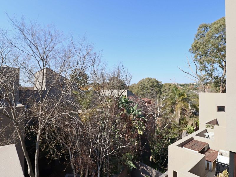 An elevated view overlooking the surrounding residential complex and mature trees, showcasing the building's exterior architecture and natural landscape.