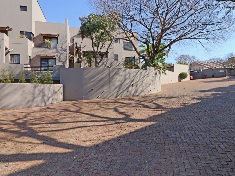 A view of the apartment complex exterior featuring a paved driveway, retaining walls, and multi-level balconies.