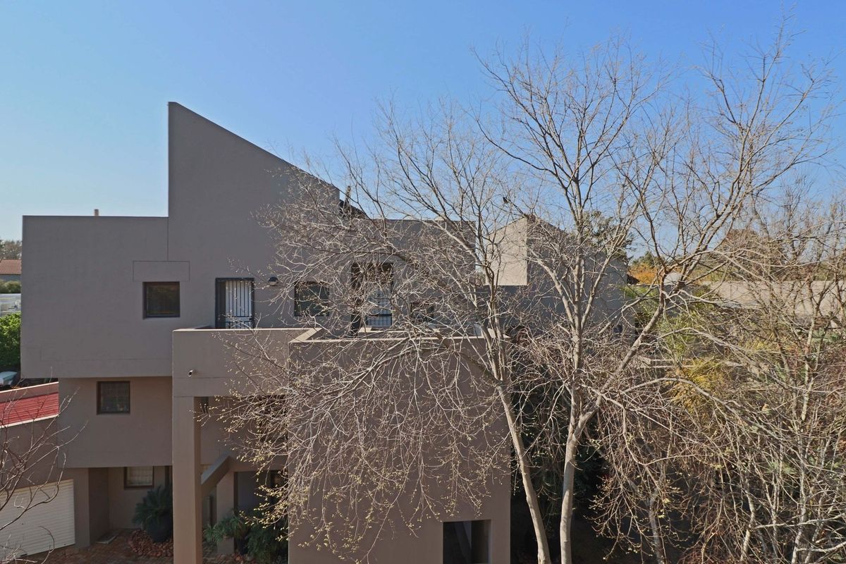 Rear elevation of a multi-level apartment building featuring modern architectural lines, balconies with security gates, and a ground-level garage.