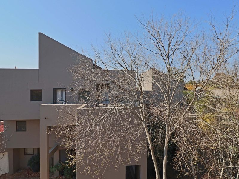 Rear elevation of a multi-level apartment building featuring modern architectural lines, balconies with security gates, and a ground-level garage.