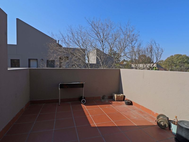 An open-air balcony featuring terracotta tiled flooring and a solid parapet wall, providing a private outdoor space.