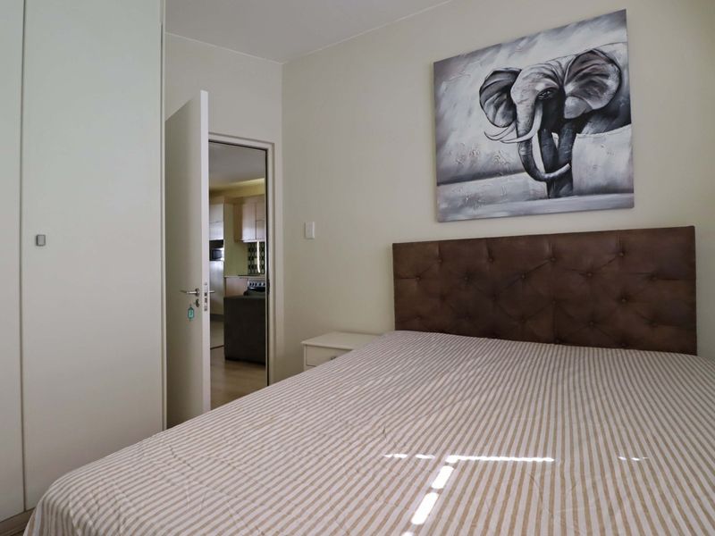 A well-maintained bedroom featuring built-in cupboards and a view through the doorway into the adjacent living area.