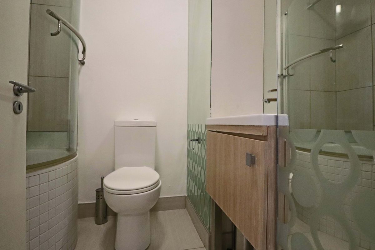 Compact bathroom featuring a shower enclosure, modern toilet, and a vanity cabinet with an integrated basin.