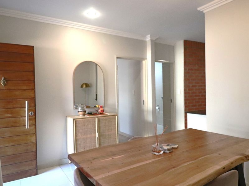 A bright living area featuring tiled flooring, crown molding, and an exposed brick accent wall, providing a warm and inviting atmosphere.
